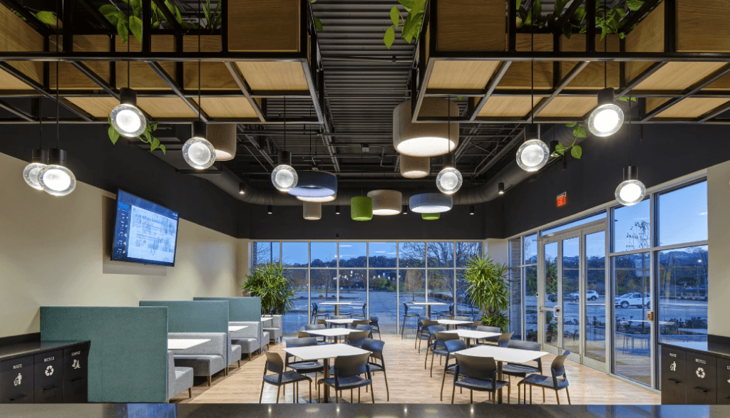 A room with tables, large windows and areas to dispose of waste, recycling and compost.